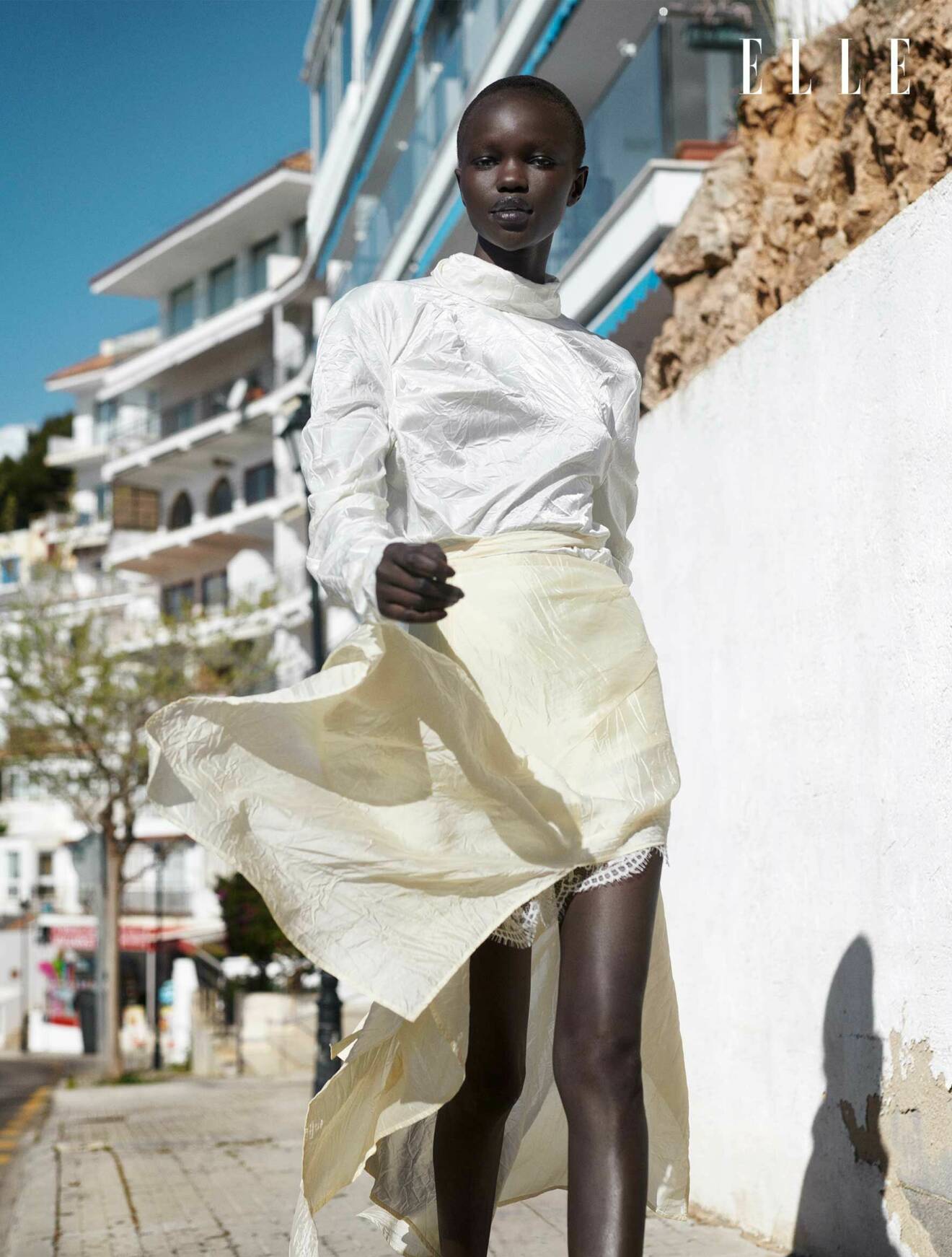 Modellen har på sig en vit topp och kjol, båda plaggen från Acne Studios