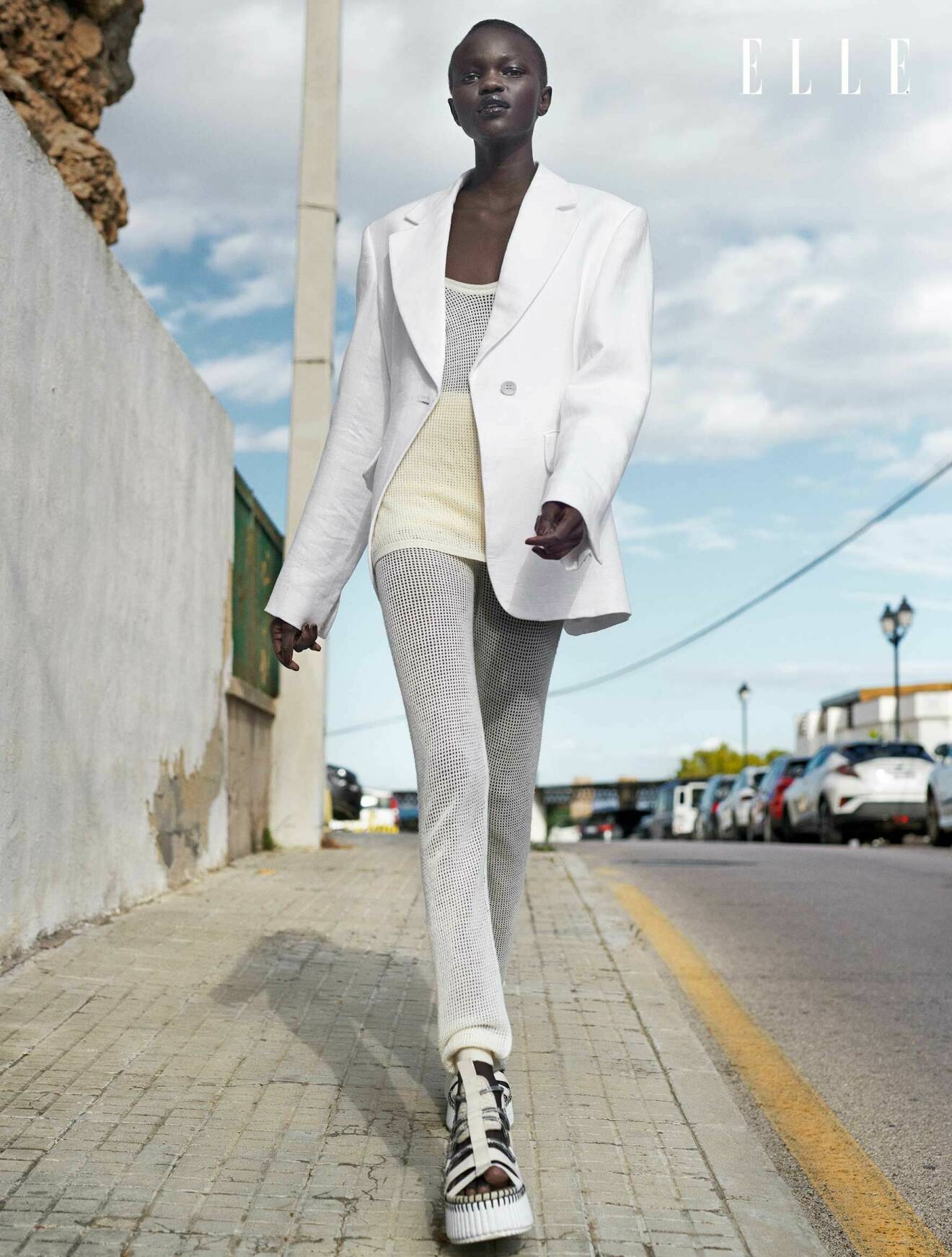 Modellen har på sig en vit kavaj, vitt linne, vita shorts med vita byxor kunder, allt från Chloé