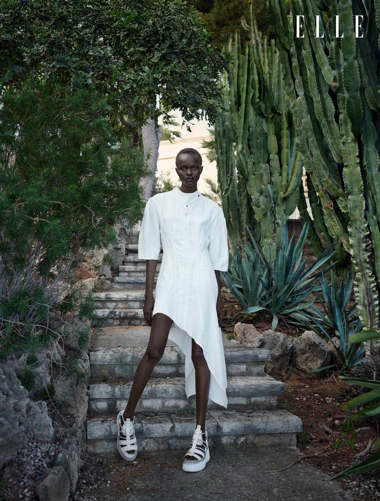 Modellen har på sig en vit klänning från Toteme och vita skor från Chloé
