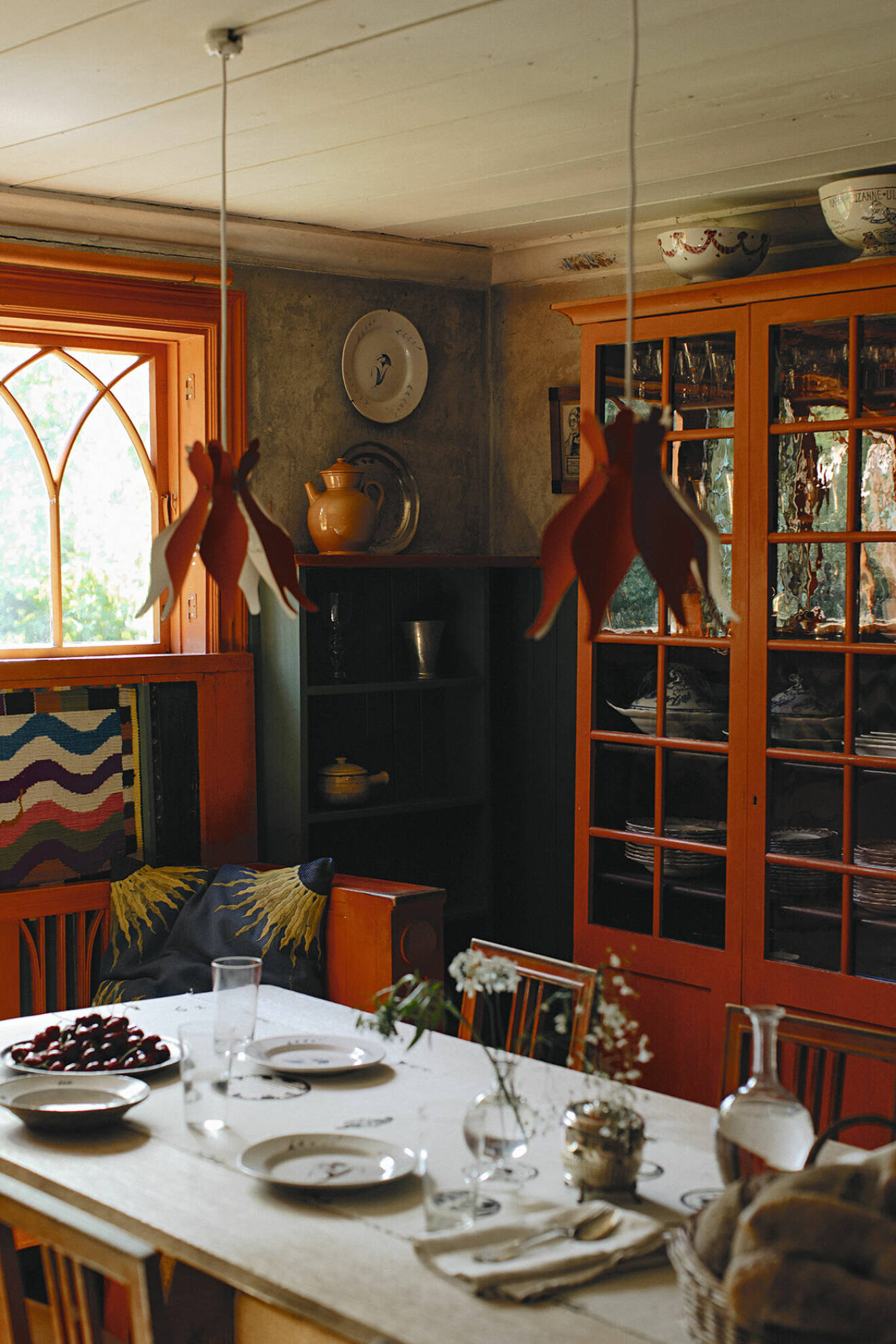 Matsalen på Lilla Hyttnäs med orangeröda snickerier och möbler. När huset fick elektricitet 1901–1902 klipptes lampskärmar av rött papper med inspiration från en blommande kaktus. I kökssoffan ligger originalversionen av Solroskudden.