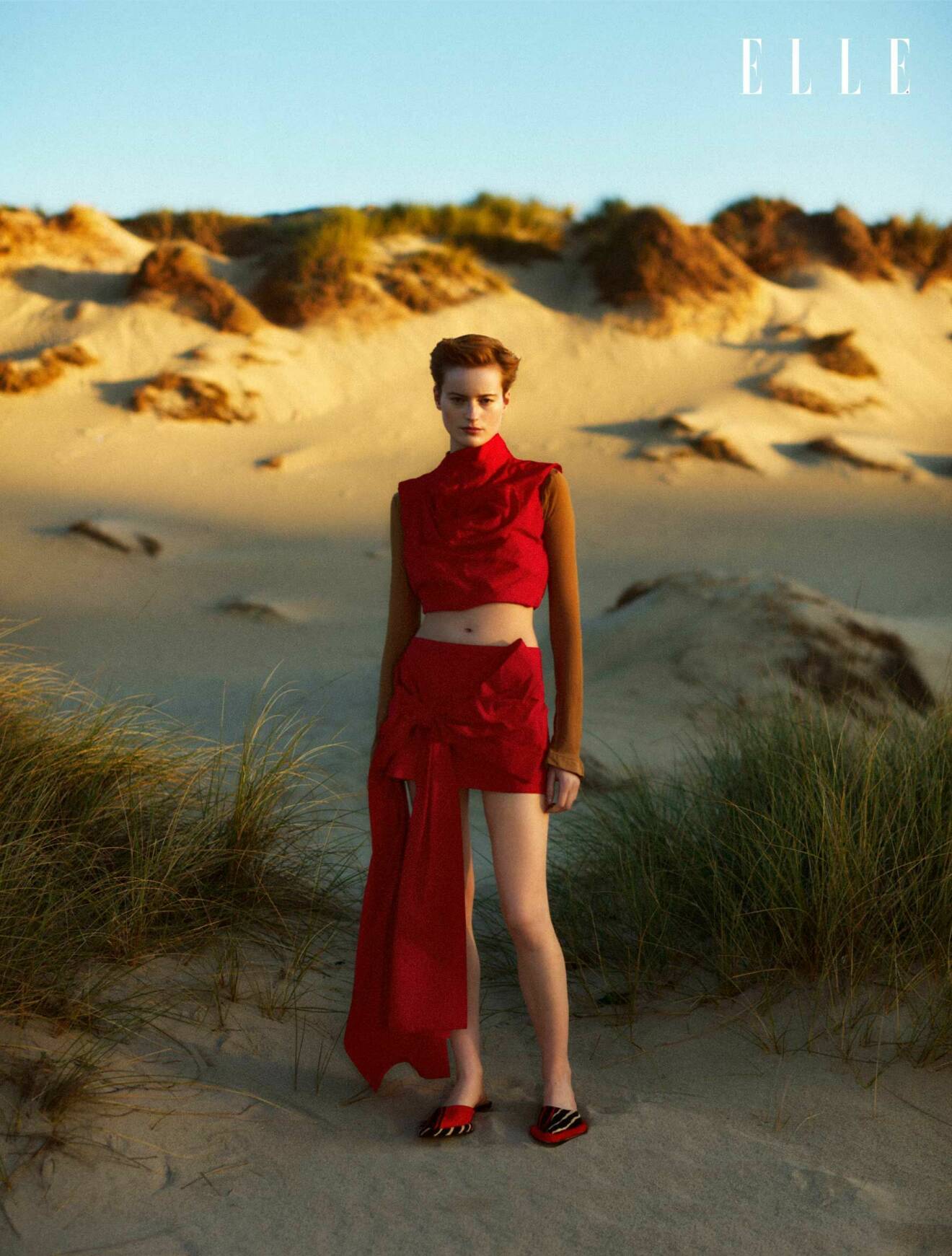 Fotomodellen har på sig en röd polotröja, topp och kjol, allt från Acne Studios.