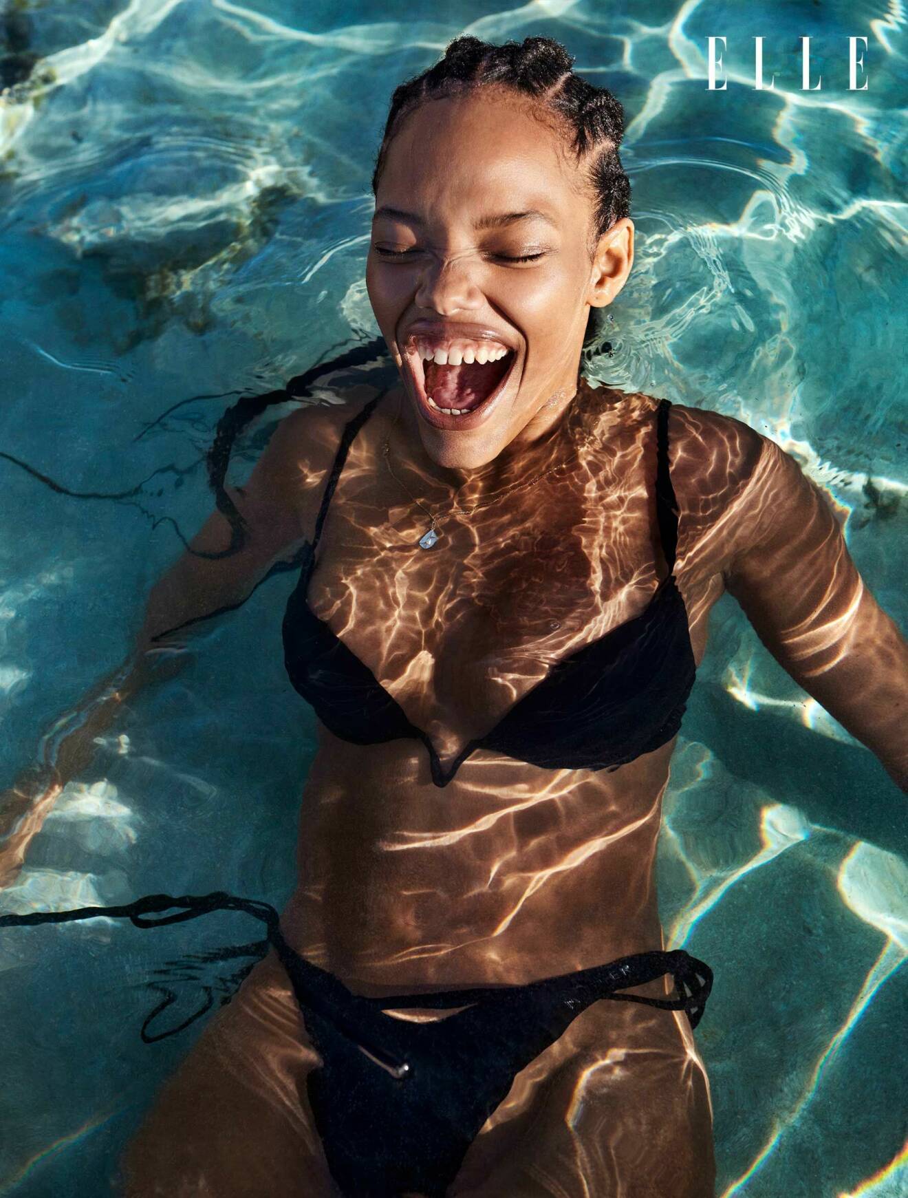 Modellen ligger i vattnet, hon har på sig en svart bikini från H&amp;M x Mugler