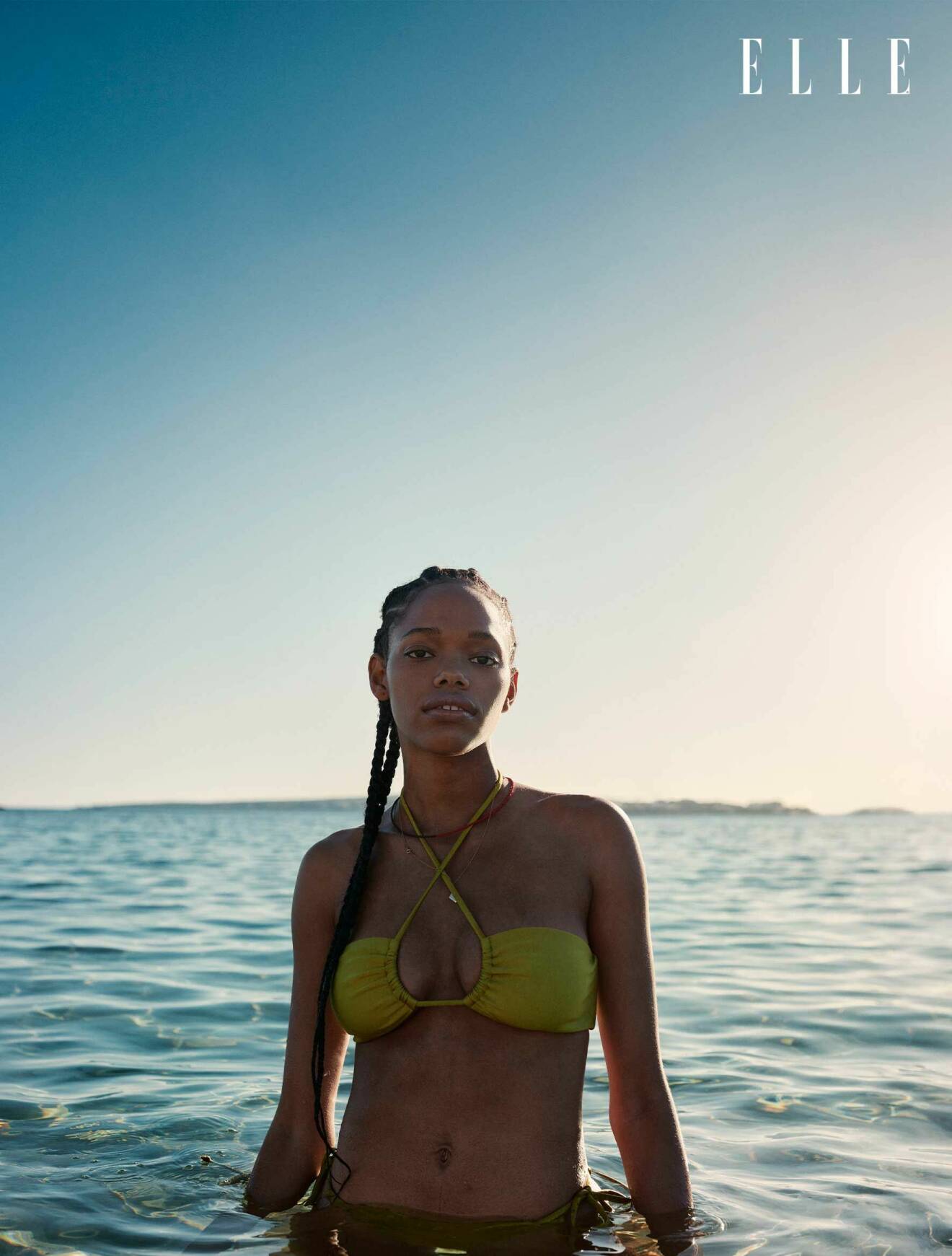 Modellen står i havet, hon har på sig en grön bikinitopp och underdel, båda från Vanessa Sposi