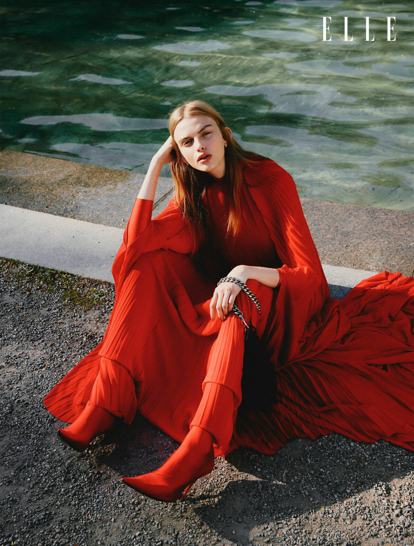 Modellen sitter ner, hon har på sig en röd maxiklänning och röda skor, allt från Balenciaga.
