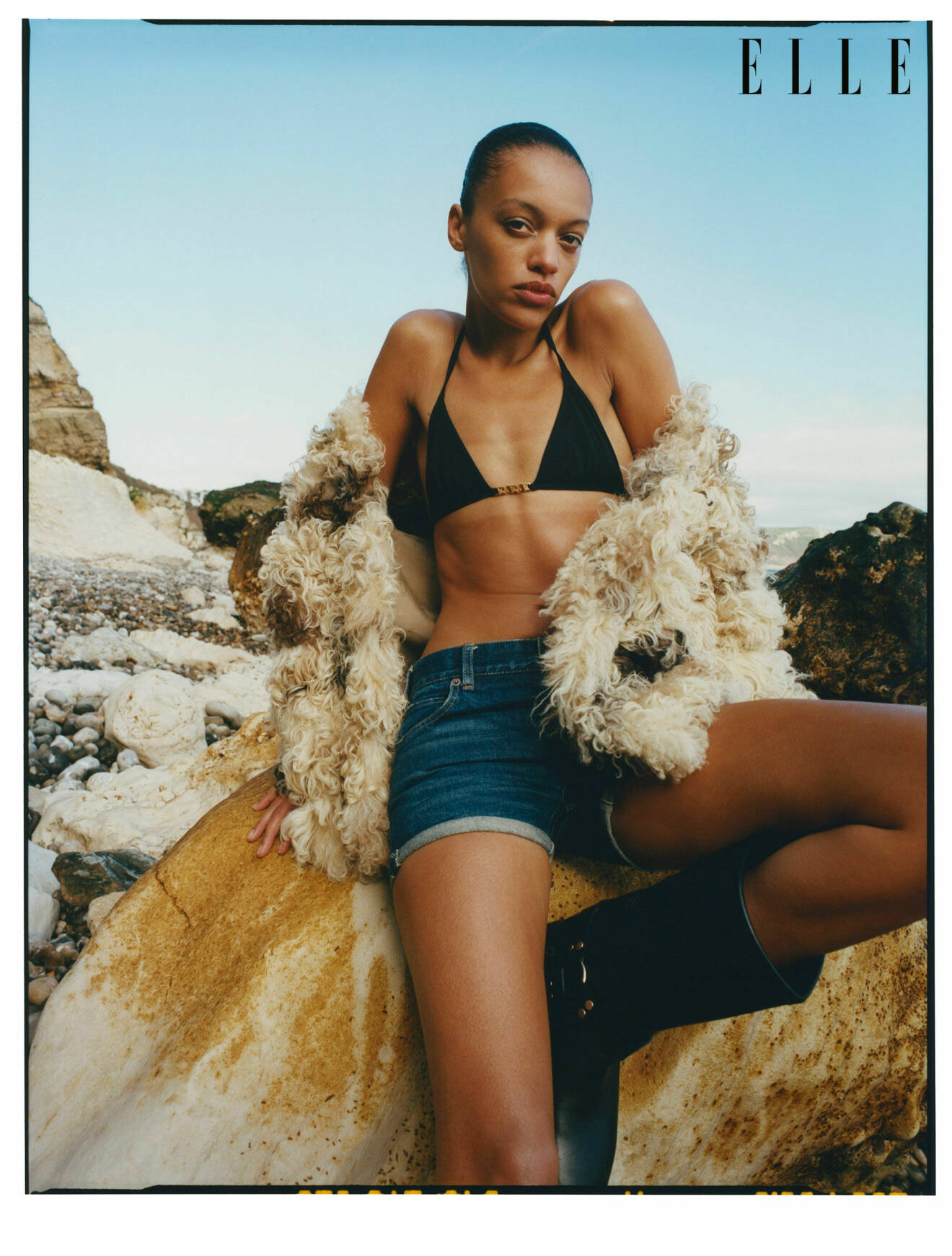 Modellen har på sig en jacka i fuskpäls, svart bikinitopp och jeansshorts, allt från Celine by Hedi Slimane.