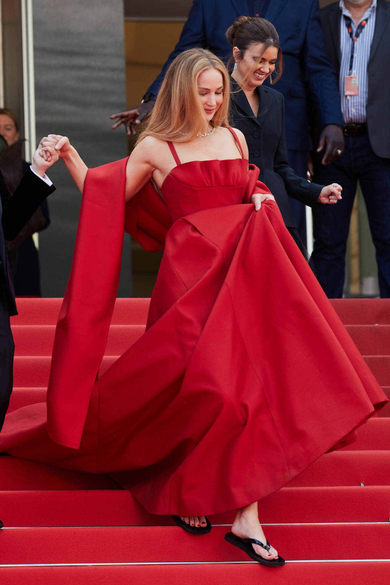 Jennifer Lawerence i röd klänning med svarta flip-flops på Cannes Filmfestival 2023
