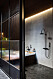 Stort badrum med skiljevägg med frostade glas och olika nyanser av svart