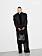 Modellen har på sig en lång kappa, tröja och byxor, allt från Saint Laurent by Anthony Vaccarello.