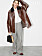 Modellen bär en brun jacka, vit skjorta och randiga byxor, allt från Louis Vuitton.