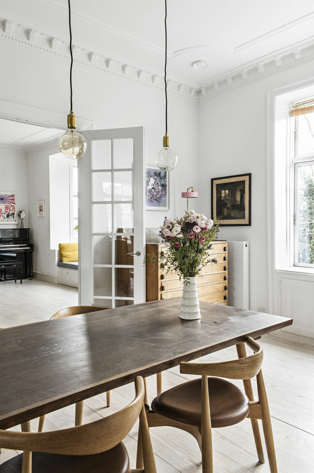 Matplats med matbord i mörkt trä och tillhörande stolar med böjd rygg