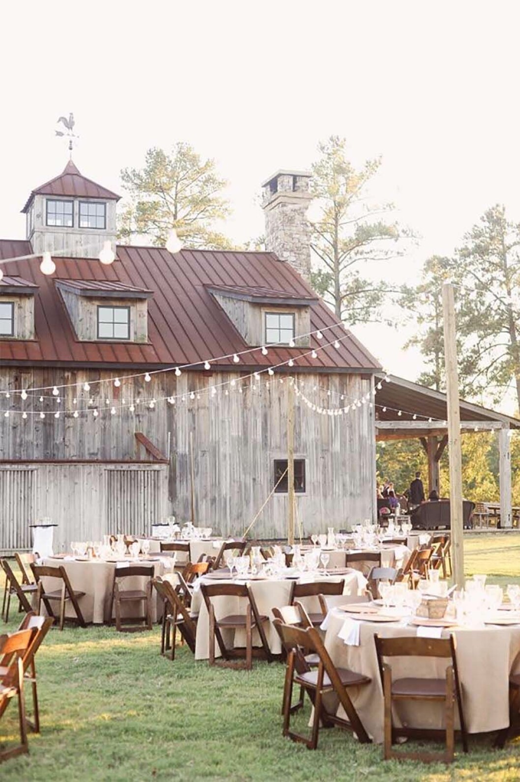 Via: <a href="http://cutediyprojects.com/wp-content/uploads/2015/02/Rustic-Outdoor-Reception-Right-Next-To-The-Barn.jpg" target="_blank" rel="noopener">Cutediyprojects</a> Uppdukade bord och festbelysning utanför en lada