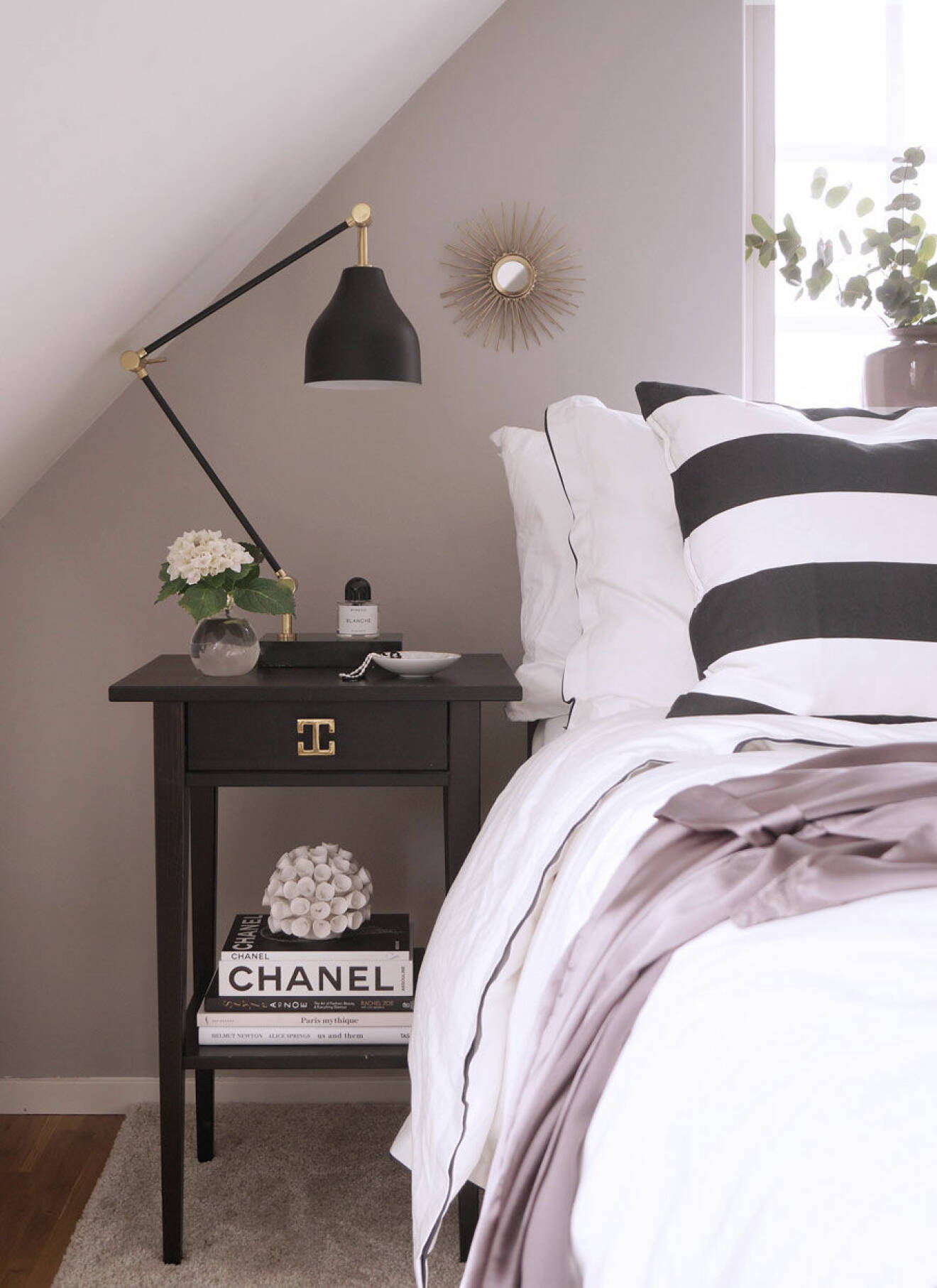Sovrum med svart och vitrandigt örngott, naturrosa väggfärg