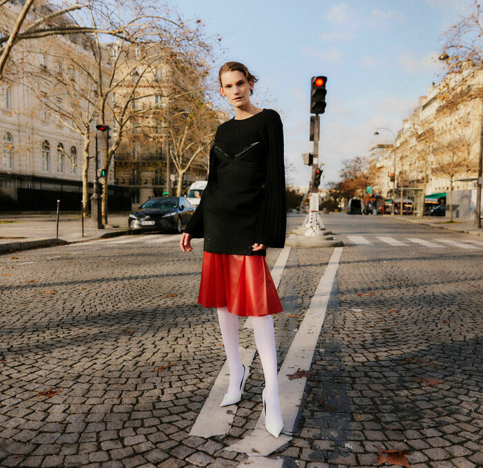 Klänning, 5 200 kr, Hodakova. Tröja, 4 500 kr, Totême. Kjol, pris vid förfrågan, Lacoste. Strumpbyxor, 79 kr, Climate Tights. Skor, 2 500 kr, Balenciaga/Vestiaire. Modellen bär en röd klänning från Hodakova med en svart tröja över från Totême