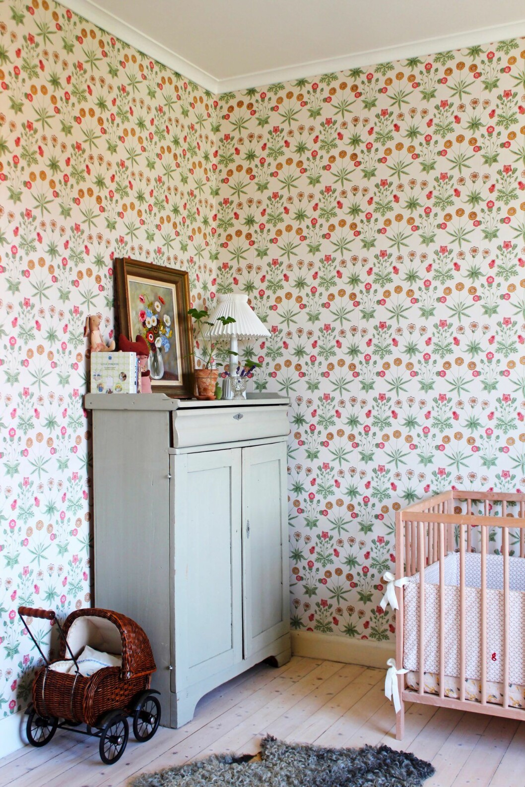 Elisabeths rum. Skåpet från Blocket köptes till vårt gamla kök. Spjälsäng, Ikea. Oljemålning med blommor, loppisfynd. Lampan <em>Esben Klint</em> är ett designsamarbete mellan Le Klint och Lyngby porcelæn. Mönstrade tapeter i barnrummet hos Johanna Bradford