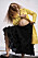 Modellen bär en gul kappa och en lång, svart kjol
