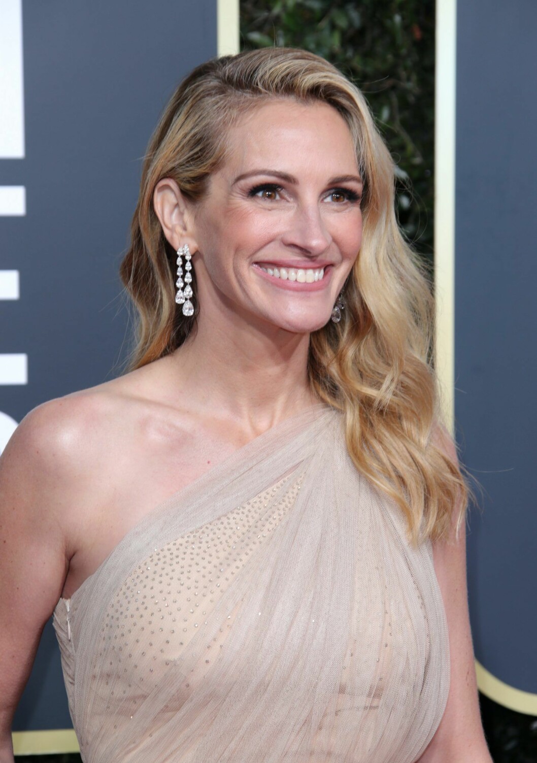 Julia Roberts är blond och har vågigt hår och ler stort.