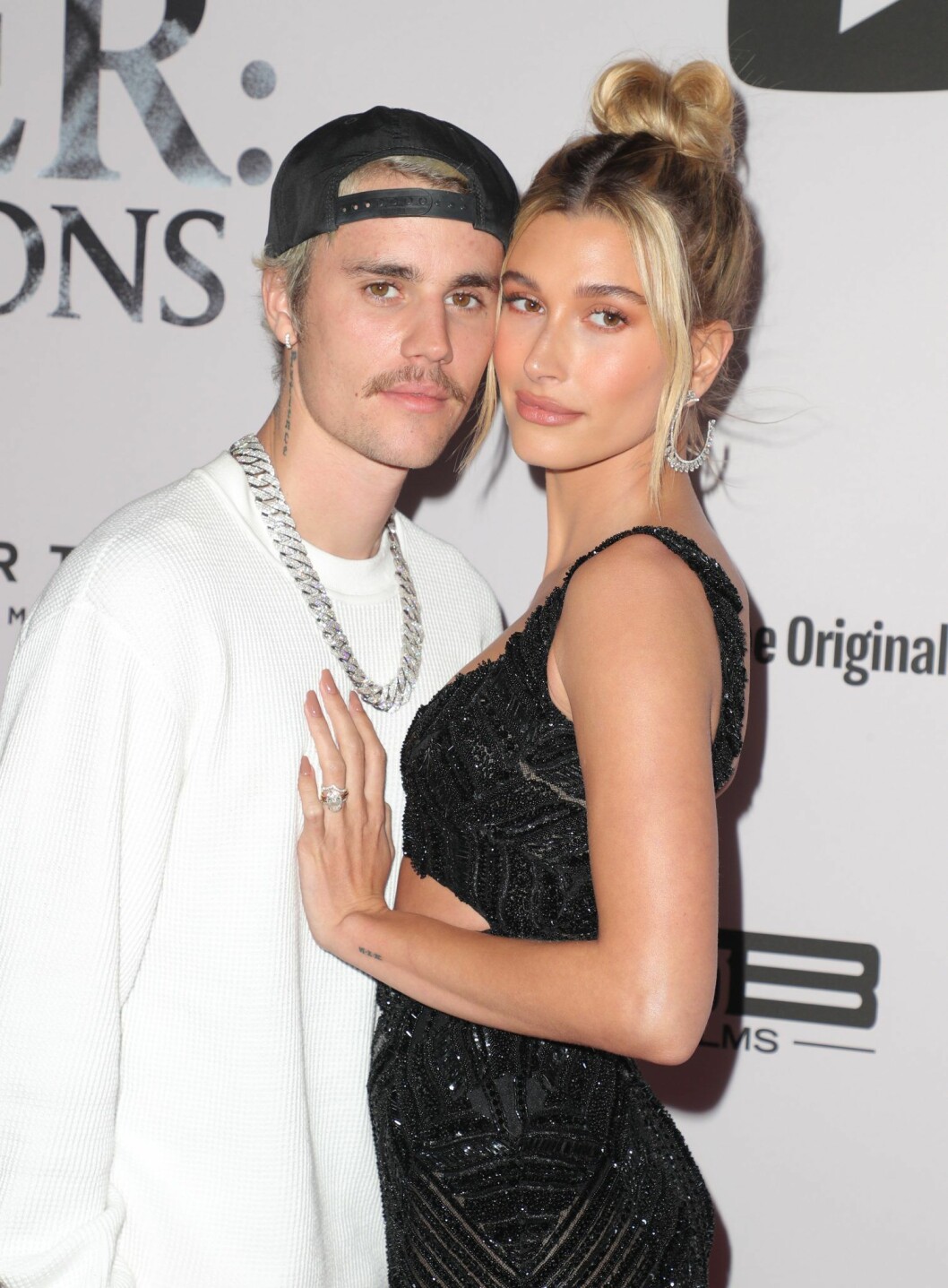 Halvkroppsbild på Justin Bieber och Hailey Bieber som står vända mot varandra och kramas