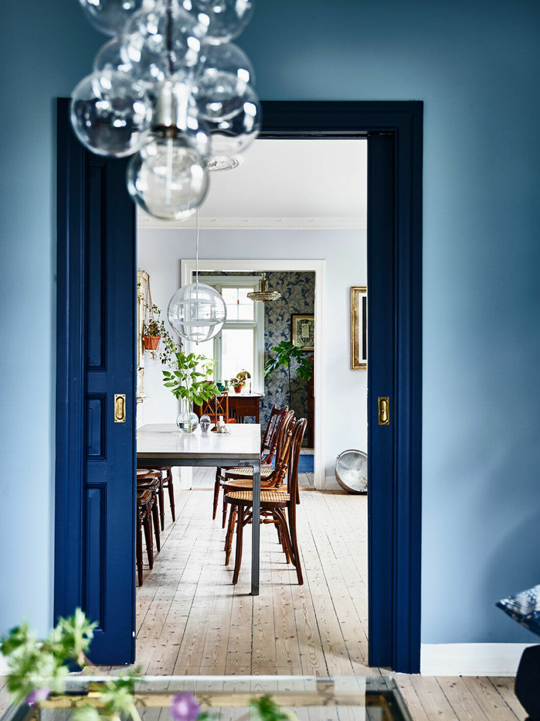Tre rum ligger i fil och är alla målade eller tapetserade i blå toner. Skjutdörren som är målad i Dark Dijon från Nordsjö blir ett utrops-tecken i hemmet och knyter ihop rummen.