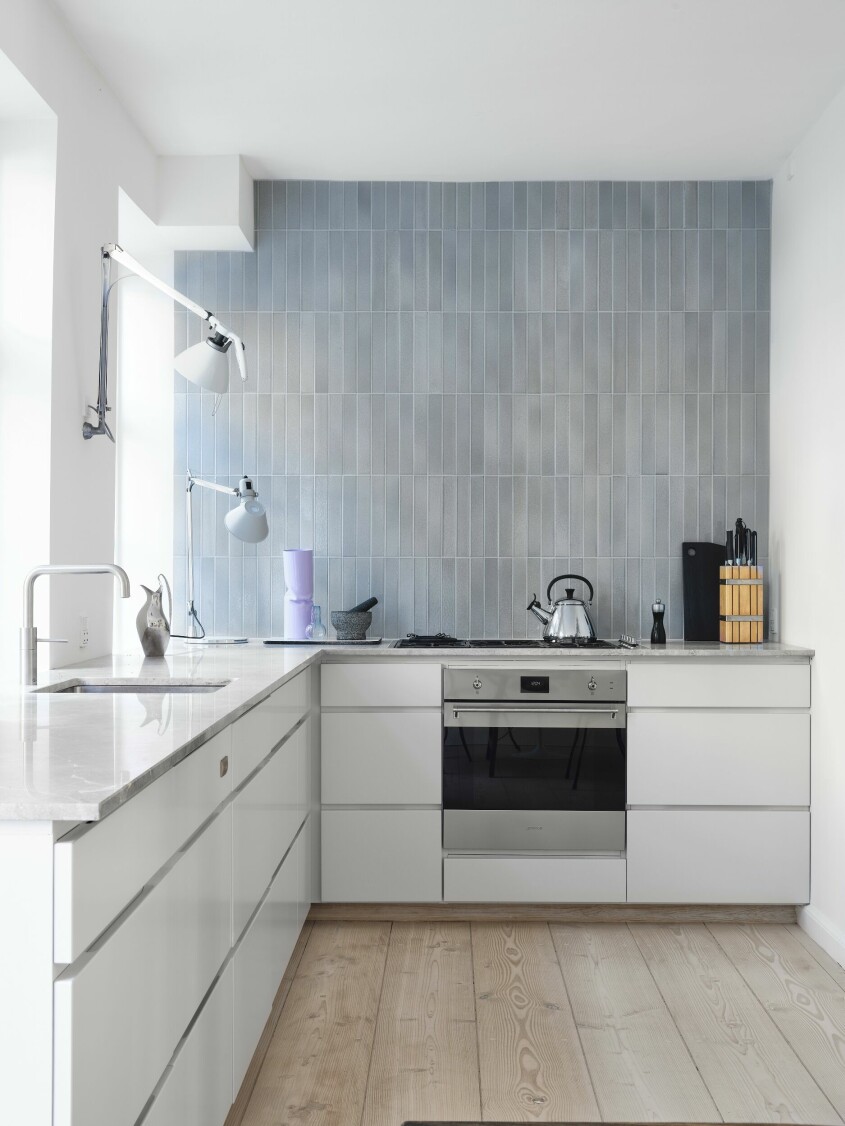Helles blekgråa Kvik-kök med lavastenskakel från File Under Pop. Den lila vasen är från Tableau. Stålkokaren är från Le Creuset och stålkannan är den ikoniska Koppel från George Jensen designad av Henning Koppel. Kvik-kök