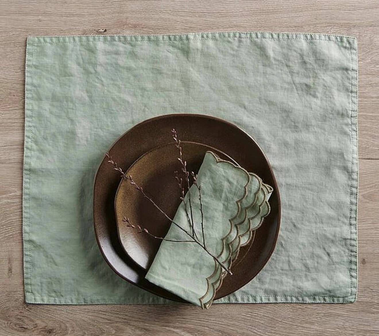 Grön bordstablett som skyddar bordet och duken i linne under.