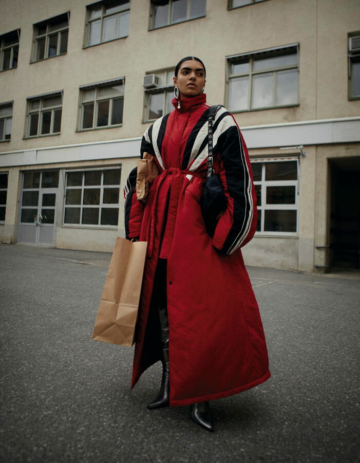 Kappa, 20 209 kr, byxa, 6 042 kr, väska, 14 725 kr, stövlar, 15 131 kr, och örhängen, 7 058 kr, allt BALENCIAGA. Modellen bär en lång, röd jacka med svartvita detaljer