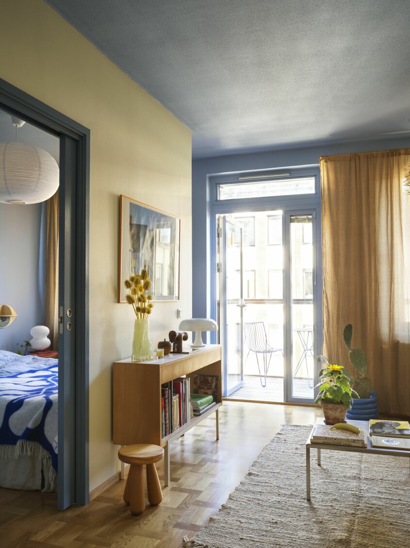 Hela lägenheten har ett genomgående färgtema med toner av blått och gult och beige. Sidobordet är vintage liksom soffbordet. Bordslampan <span class=" italic" data-lab-italic_desktop="italic">Nessino</span> är från Artemide. Målade tak