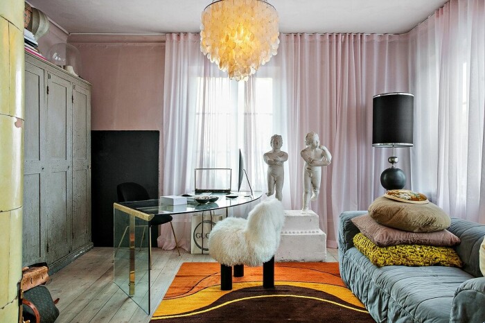 Hemmakontor i toner av mjukt rosa, med väggar målade i kalkfärg och skira gardiner som går ton i ton med väggen. Här finns en av bostadens många kakelugnar.
