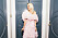 Emilia De Poret i fluffig rosa klänning vid blåa dörrar.