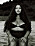 Modellen sitter på stranden i en svart bikini