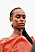 Närbild på modellen som har ansikte och axlar täckt i rosa glitter och bär en röd klänning från Sportmax