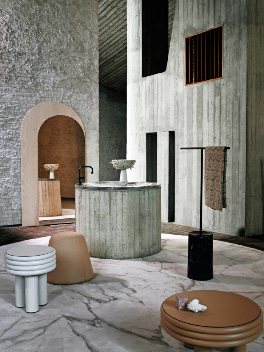 Matta <em>Sense of Marble</em>, Dessa. Vit läderpuff, Giobagnara. Rosa puff, design Mile & Maaike, Artifort. Spegel <em>Buzzi Mirage XL</em> av Alain Gilles, Buzzispace. Kran från Gessi. Skål <em>Celestial Bowl</em> av Elad Yifrach, L’Objet/Edha Interieur. Handdukshängare <em>Tonbo</em>, Living Livani. Handduk <em>Vanni</em>, Missoni. Brun läderpuff <em>Scala</em>, Giobagnara. Skulpturer <em>Landscape Portrait #3</em>, Studio Thinkinghand. Små inredningsdetaljer som pallar och bord i olika storlekar och ton i grått rum