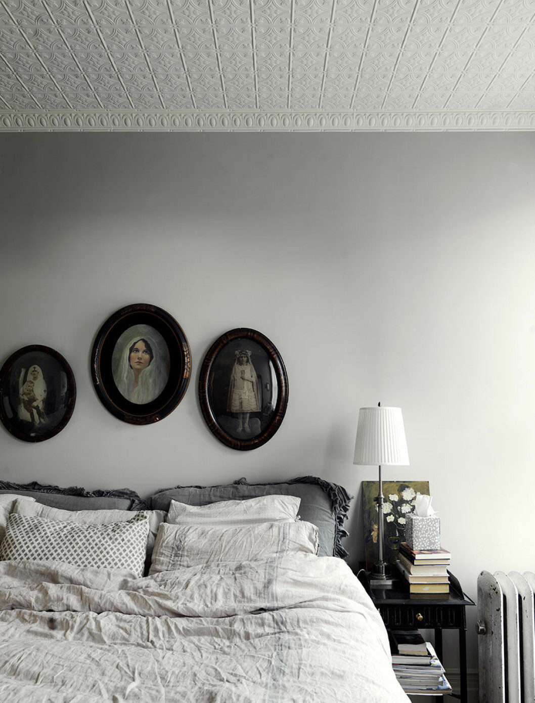 En trappa upp har även Nina och Nathan sitt sovrum. De gamla porträtten ovanför sängen är köpta på loppis och E-bay. Lakanen i linne kommer från Restoration Hardware och Matteo. Sovrummet i lägenheten.