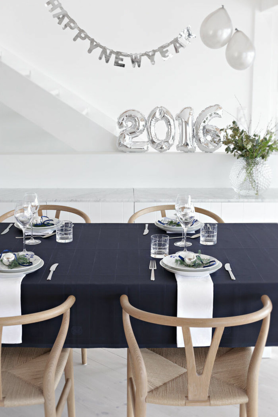 Nyårsdekorationerna och dukningen kan vara precis lika stämningsfulla i minimalistisk tappning. Foto: <a href="https://stylizimoblog.com/2015/12/31/table-setting-new-years-eve/" target="_blank" rel="noopener">Nina Holst/Stylizimo</a> avskalad dukning till nyår i silver och vitt
