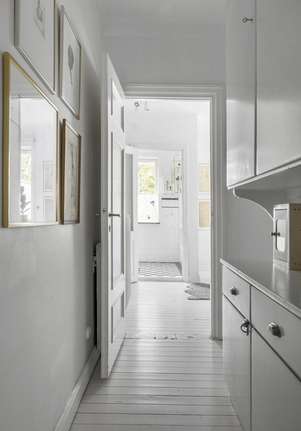 Vitmålad hall med tavlor