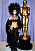 Cher i svart fjäderhatt och svart avslöjande zickzack-klänning