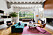 Vardagsrummet med turkos soffa, ljusrosa matta och mängder av färgglada små och stora inredningsdetaljer