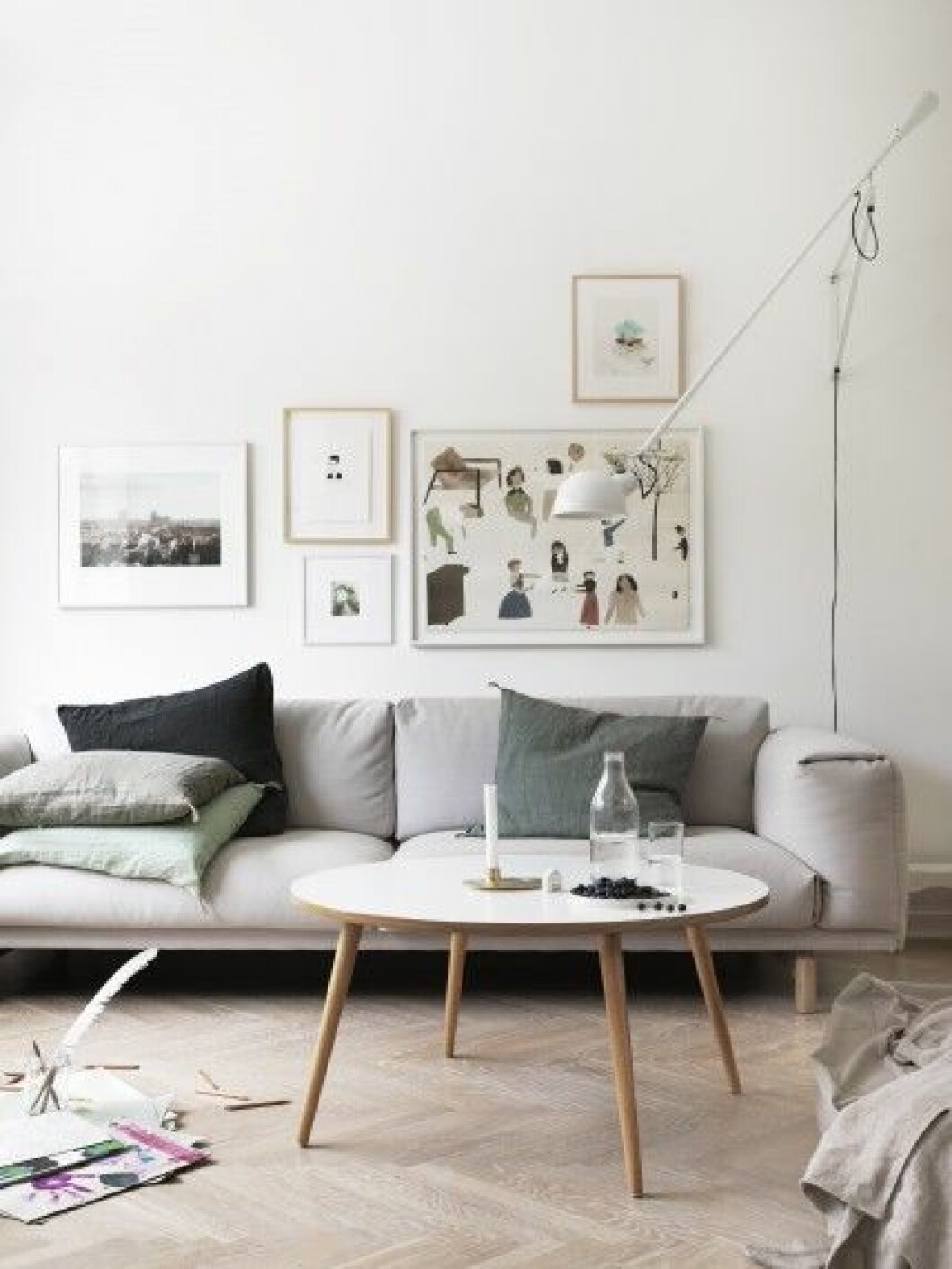 Vardagsrummet ligger ut mot den lilla trädgården. Soffan Rest kommer från Muuto, som Petra har jobbat mycket för. Kuddar från Norrgavel och Society. Soffbordet är designat av arkitekten Carl Engblom, som själv har bott i Friluftsstaden i Malmö. Lampan på väggen kommer från Flos. <br>– Eftersom skapandet av ett hem handlar om kreativitet uppskattar jag den positiva energi som finns i hem som är väl omhändertagna. Men vi vet ju alla att verklighetens hem nästan aldrig ser ut som i ett inredningsreportage, åtminstone inte när man har barn. Man städar och två timmar senare har de varit framme och skapat det stök och liv i hemmet som är så underbart att leva i, säger Petra. vardagsrum tavelvägg grå soffa snygg vägglampa hemma hos petra bindel