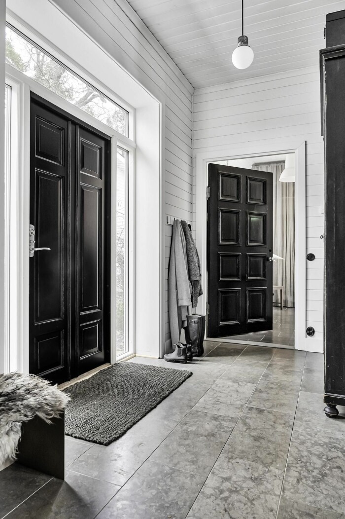 Hallen med tre meters takhöjd och kontrasterande svarta dörrar. hall med svarta dörrar och vita väggar
