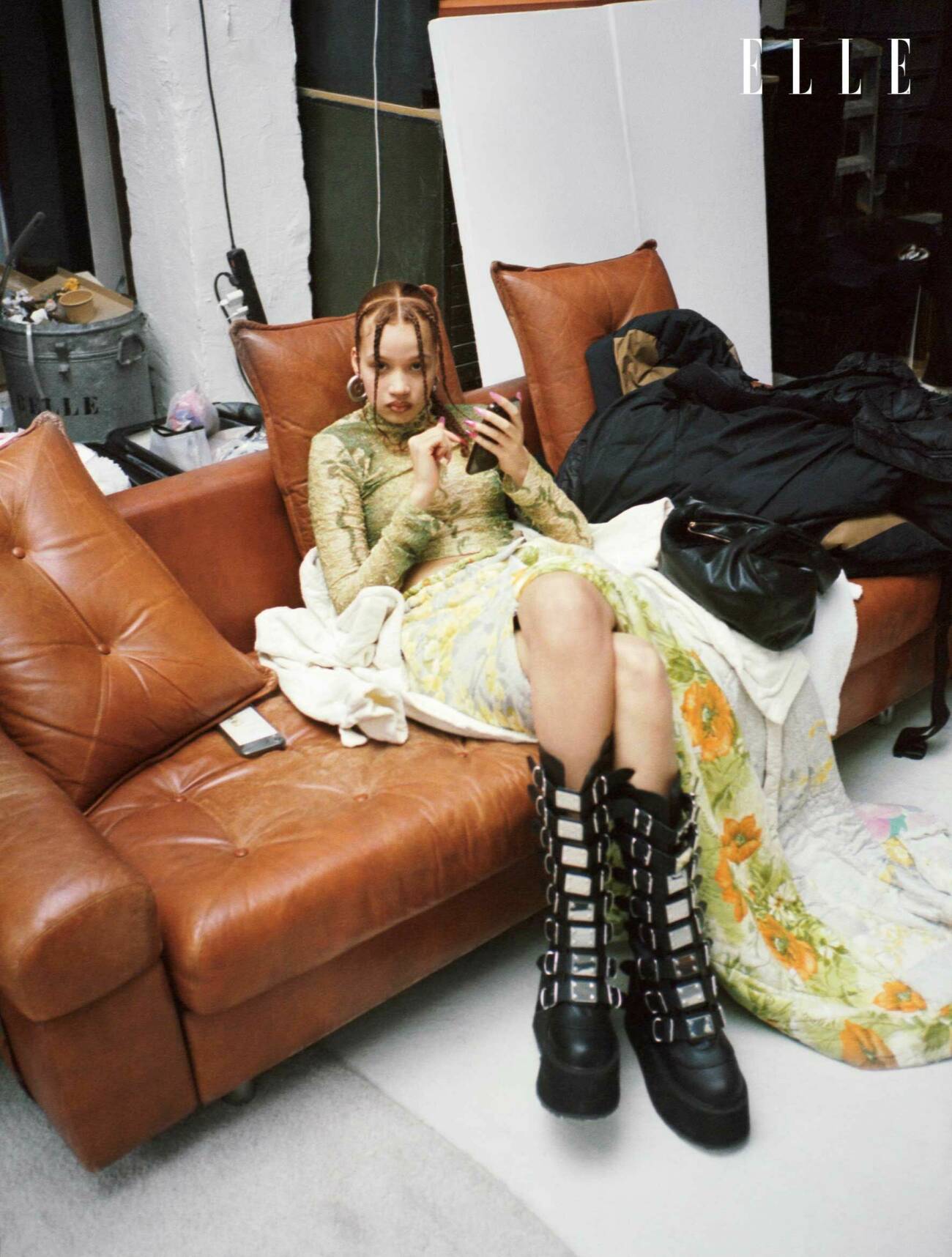 Modellen sitter i en soffa, hon har på sig en matchande kjol och topp med svarta platåboots.