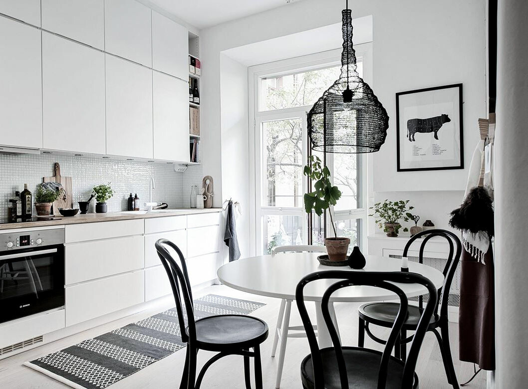 Foto: Maria Sahlander Styling: By Bon Interior för <a href="https://www.instagram.com/bjurfors_goteborg/" target="_blank" rel="noopener">Bjurfors</a>/mäklare: Maria Adielsson Vitt kök, runt matbord med svarta stolar.