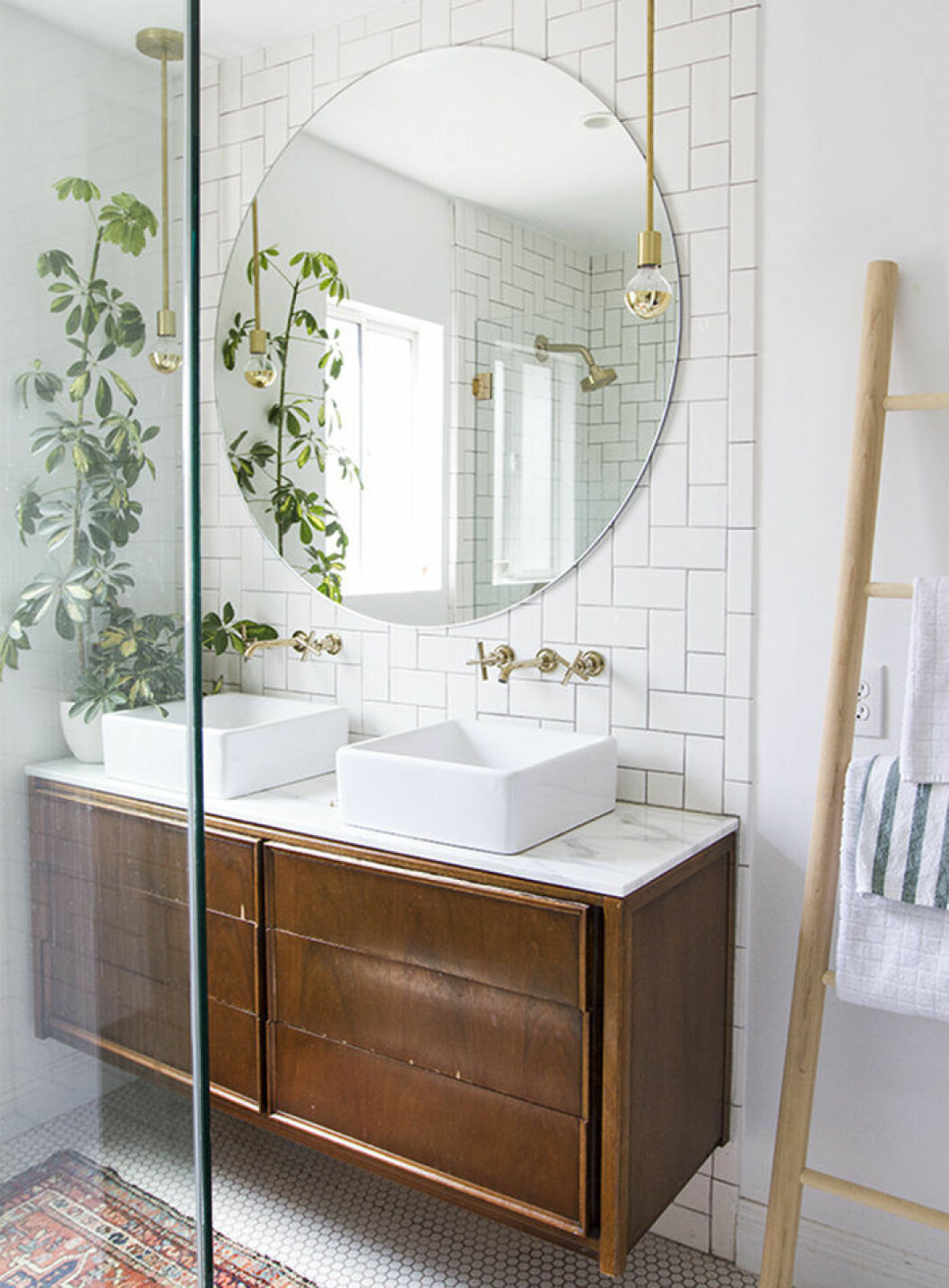 Foto: <a href="http://sarahshermansamuel.com/master-bath-final-tour/" target="_blank" rel="noopener">Sarahshermansamuel.com</a> Badrum med träförvaring, rund stor spegel och kakel i vitt