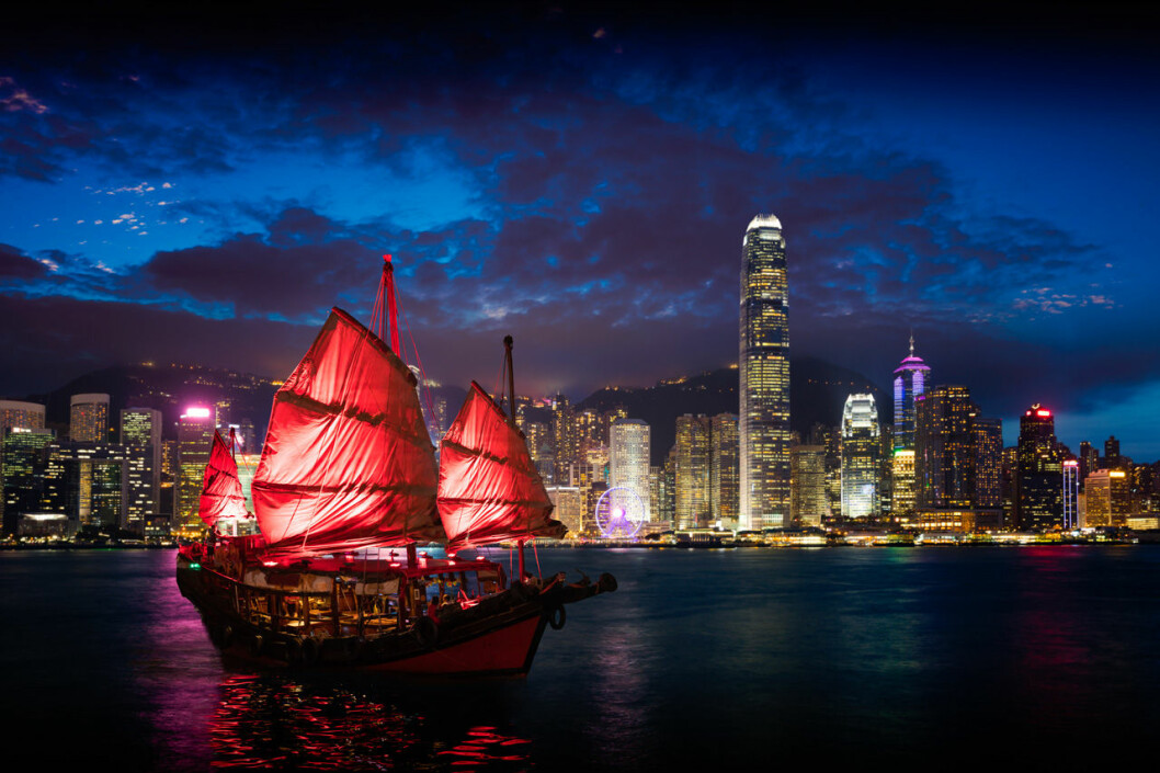 Hong Kong på kvällen med asiatisk röd båt