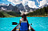 Kvinna paddlar kanot på sjö bland bergen i Kanada