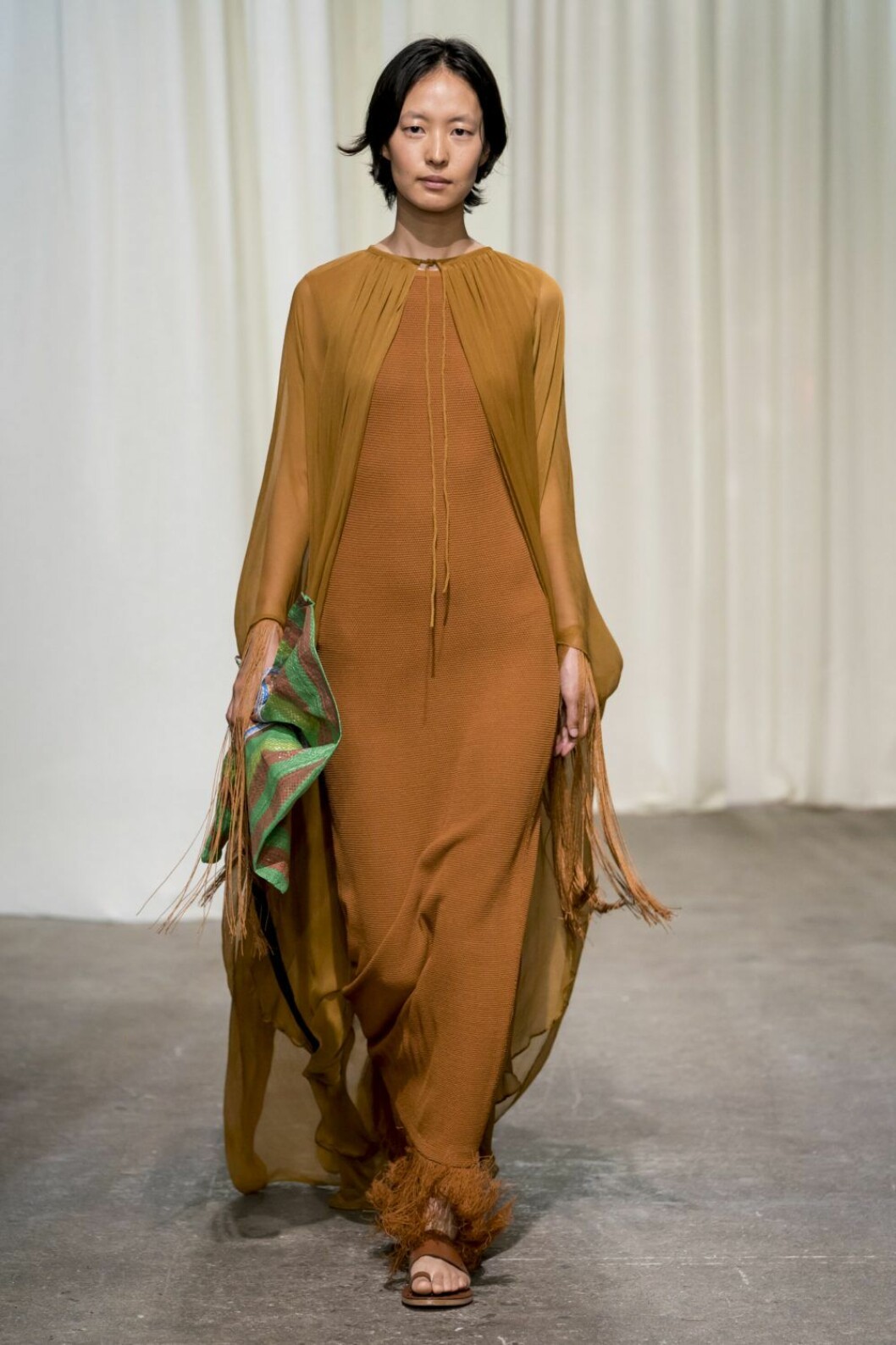 Rodebjer SS20, lång klänning i nyans av terracotta och sandaler med fransar.