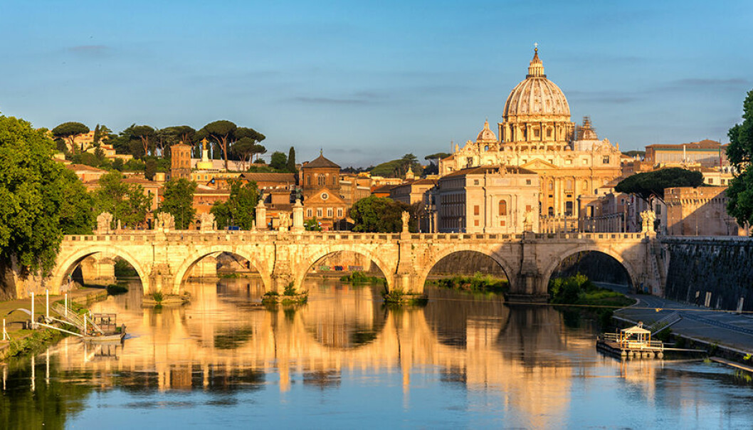 Sunrise landscape view in early morning of St. Peters Basilica in the Vatican and the Ponte Sant'Angelo, Bridge of Angels, at the Castel Sant'Angelo and river Tiber in Rome, Italy;
