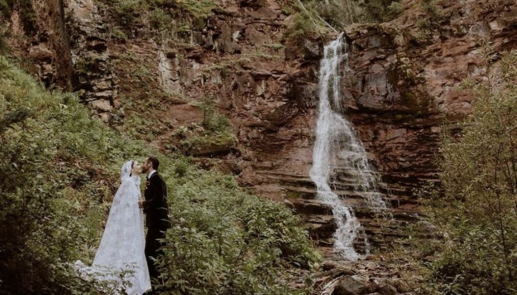 lily collins i bröllopsklänning vid ett vattenfall kysser nyblivna maken charlie mcdowell.