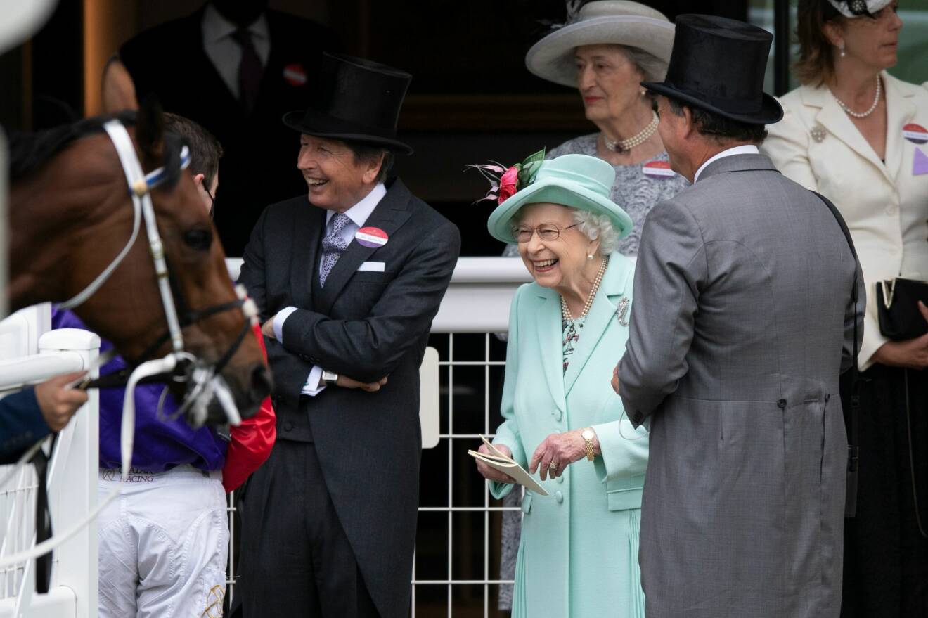 Drottning Elizabeth ler och kollar på en häst.