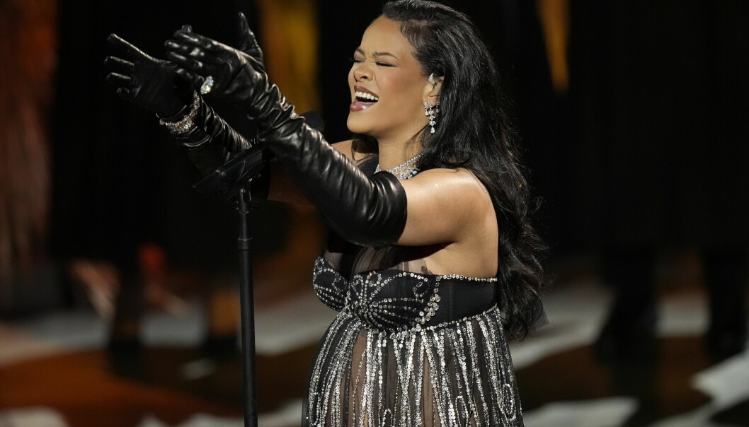 Rihanna i halterneck topp i tyll och krisatller. Svarta handskar med ring och armband. Hon bär diamant örhängen och halsband