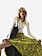 Modellen bär en gul kjol med fransar, en vit långärmad topp och en svart väska, allt från Bottega Veneta