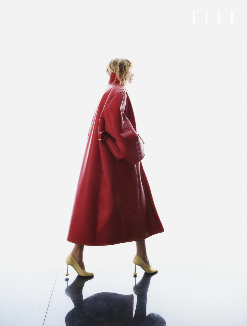 Fotomodellen har på sig en lång röd kappa från Stand Studios och en röd väska från Acne Studios